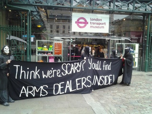Protesters dressed as Grim Reapers holding a banner that reads: "Think we're scary? You'll find ARMS DEALERS INSIDE!"