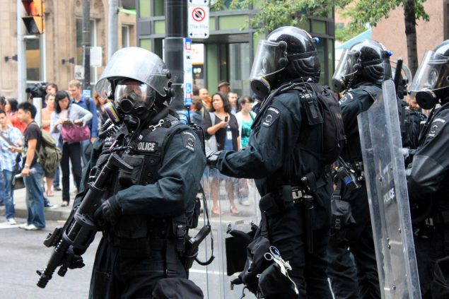 Police in heavily armoured riot gear with guns and shields