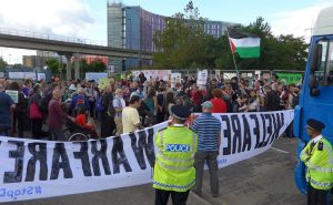 A crowd of protesters block vehicle from entering DSEI