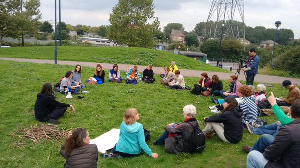 A group of people sit in a circle on the grass