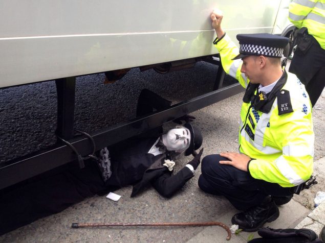 Charlie Chaplin locked on under a lorry - a police officer is trying to speak to him