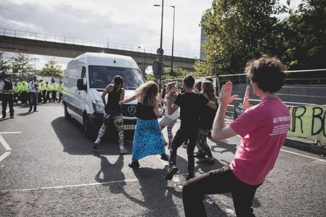 people dance in nthe road in front of a van